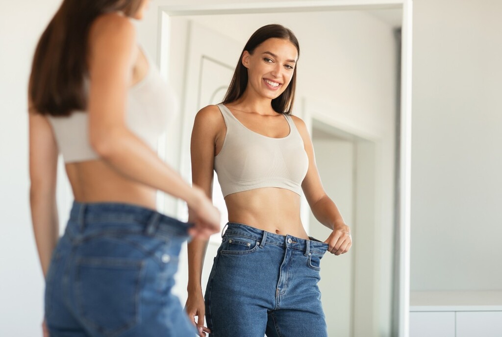 woman wearing oversized jeans after weight loss