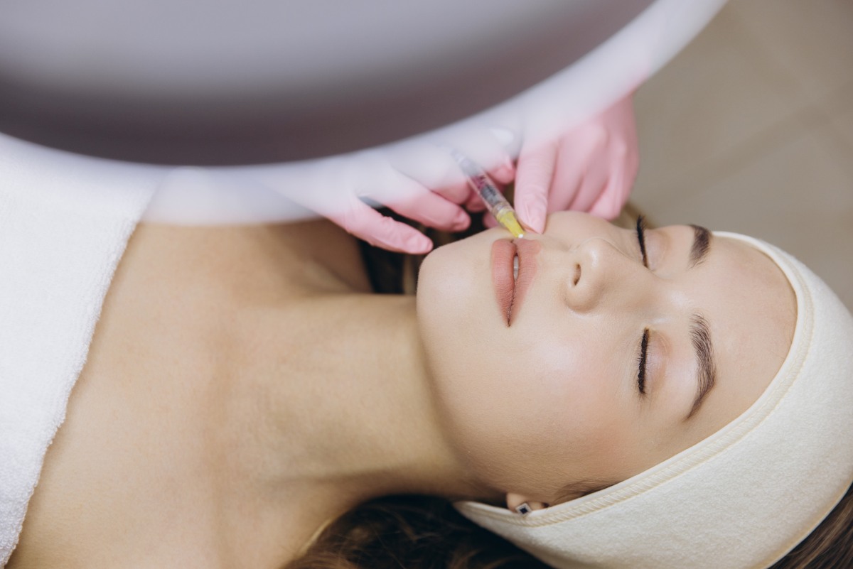aesthetics professional injecting hyaluronic acid lip filler into patient's lips for lip augmentation