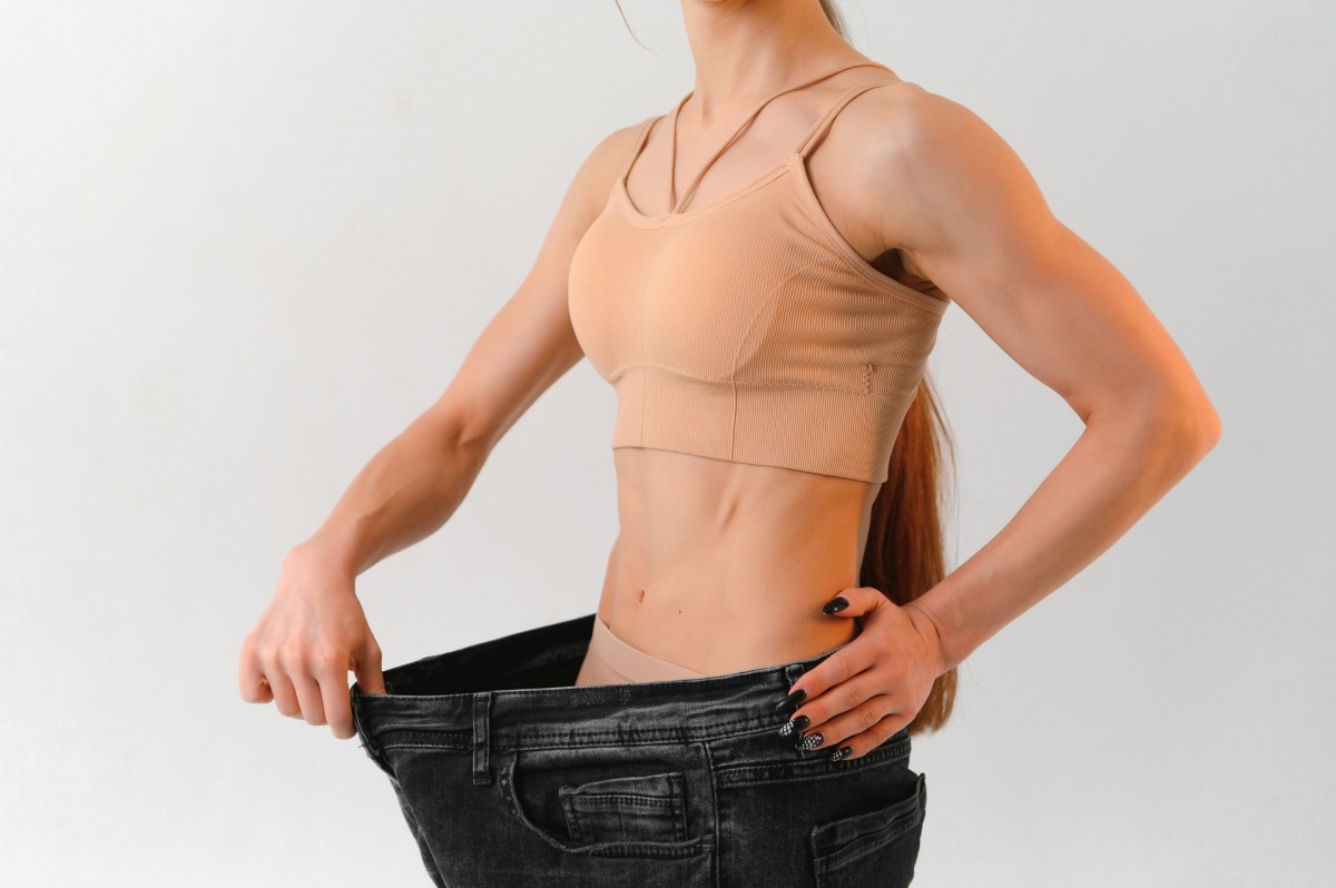 A slim woman is showing how much weight she lost