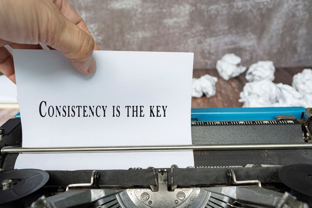 Hand pulling a piece of white paper with quote from an old classic typewriter